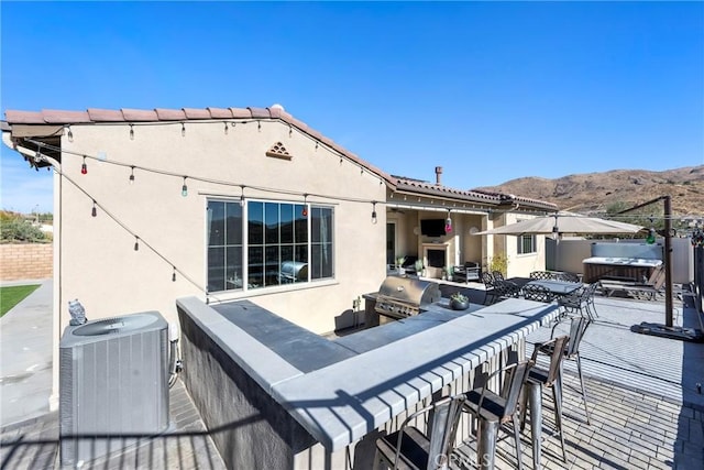 view of patio / terrace featuring central AC, area for grilling, a bar, and a hot tub