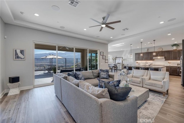 living room featuring light hardwood / wood-style floors, ceiling fan, and sink