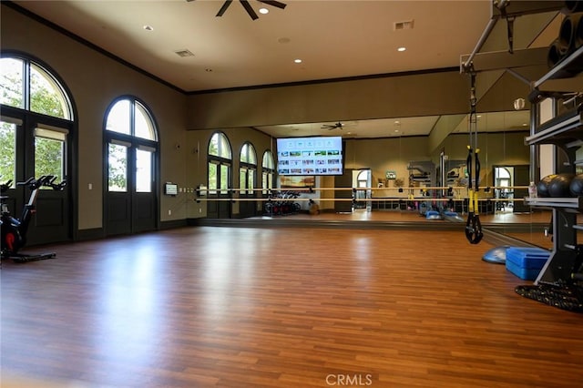 exercise room featuring ceiling fan, wood-type flooring, and ornamental molding