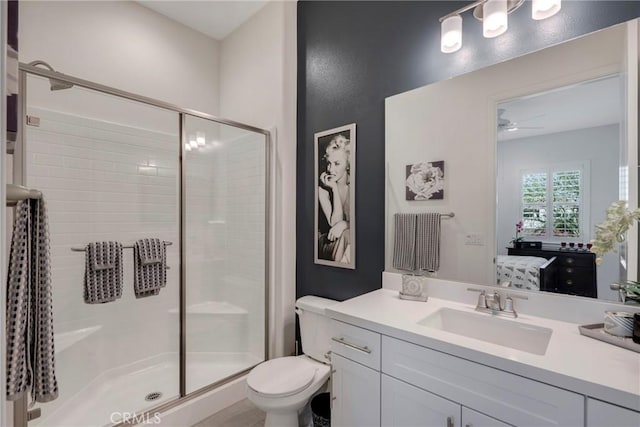 bathroom featuring vanity, toilet, walk in shower, and ceiling fan