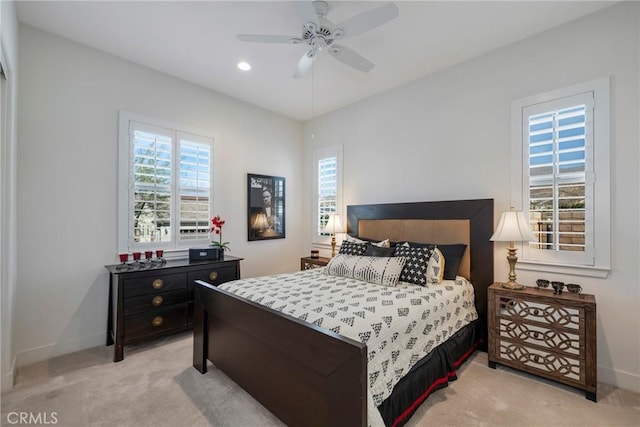 bedroom with ceiling fan, light carpet, and multiple windows