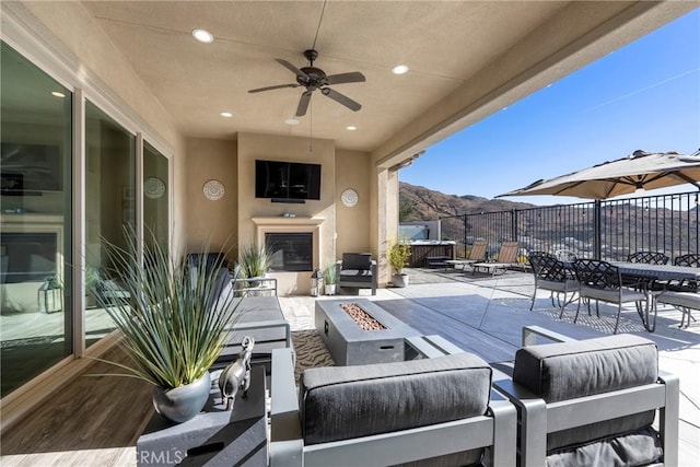 view of patio / terrace featuring ceiling fan and an outdoor living space with a fire pit