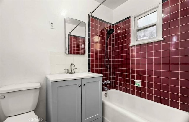 full bathroom featuring tiled shower / bath combo, toilet, and vanity