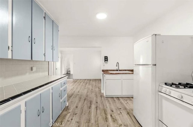 kitchen with tasteful backsplash, sink, white range with gas cooktop, and light hardwood / wood-style flooring