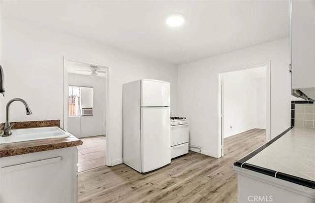 kitchen with light wood-type flooring, white appliances, cooling unit, sink, and white cabinets