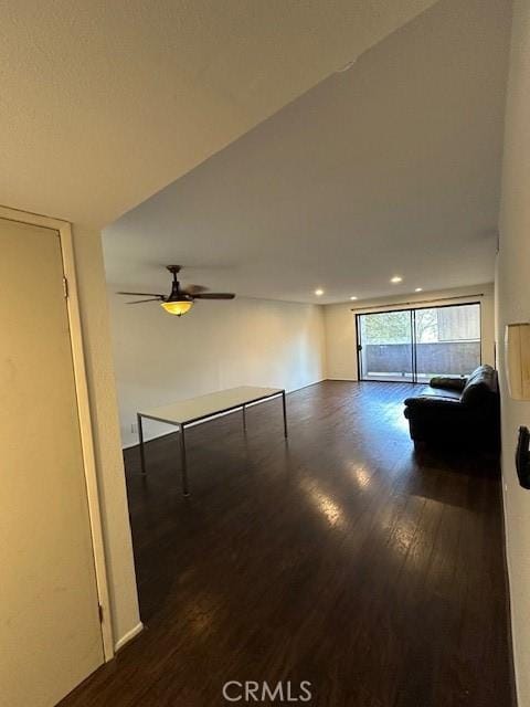 unfurnished living room with ceiling fan and dark wood-type flooring