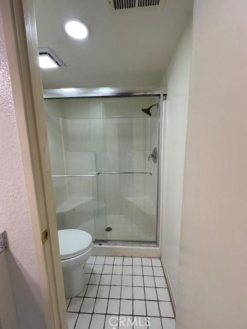 bathroom featuring tile patterned flooring, toilet, and an enclosed shower