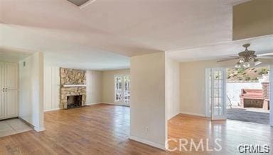 unfurnished living room featuring a stone fireplace, ceiling fan, and wood-type flooring