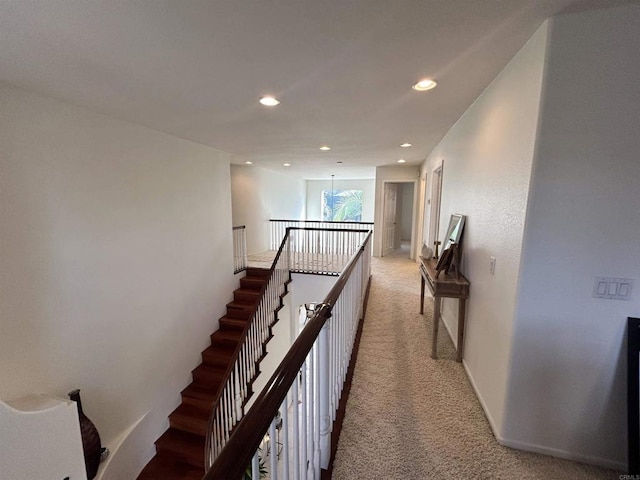 hallway featuring an inviting chandelier and light colored carpet