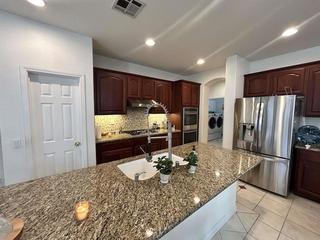 kitchen with stainless steel appliances, tasteful backsplash, light tile patterned flooring, stone countertops, and washing machine and dryer