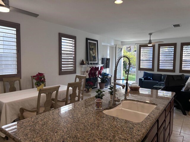 kitchen with ceiling fan, light tile patterned floors, a kitchen island with sink, and sink