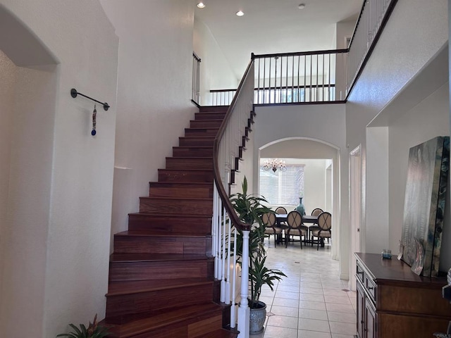 stairway with a chandelier, tile patterned floors, and a towering ceiling