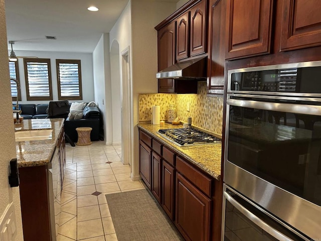 kitchen featuring tasteful backsplash, light stone countertops, stainless steel appliances, and light tile patterned flooring