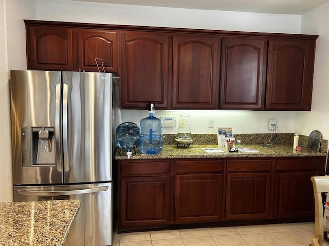 kitchen with dark stone counters, stainless steel fridge with ice dispenser, and light tile patterned flooring