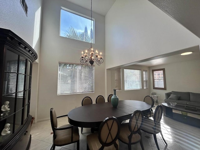 dining space with light tile patterned flooring, a towering ceiling, and a notable chandelier