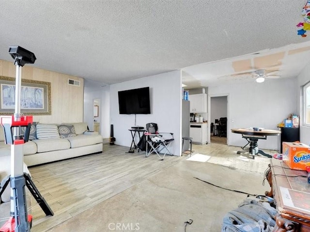 living room featuring ceiling fan, light hardwood / wood-style flooring, and a textured ceiling