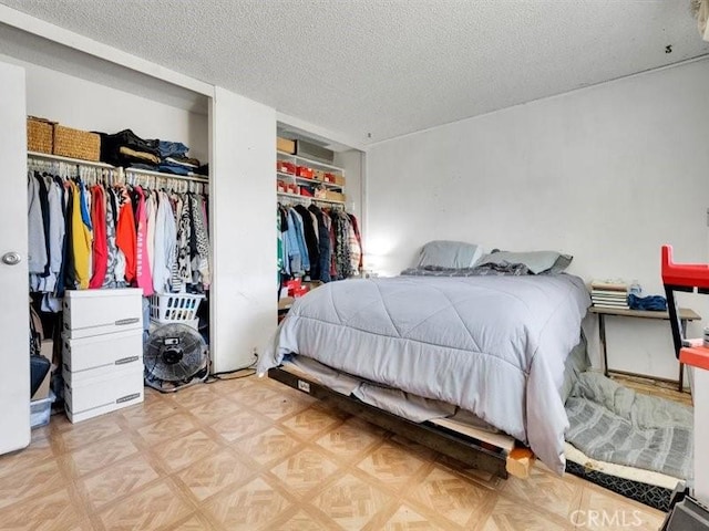 bedroom featuring a textured ceiling, a closet, and parquet floors