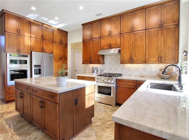 kitchen featuring sink, light stone counters, backsplash, a kitchen island, and appliances with stainless steel finishes