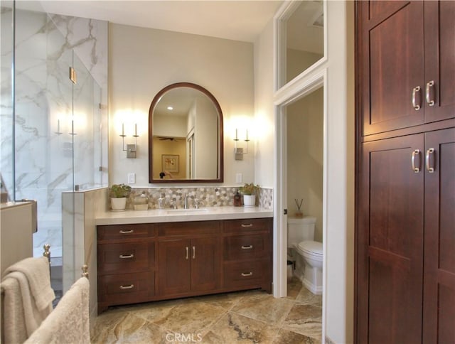 bathroom with walk in shower, backsplash, vanity, and toilet