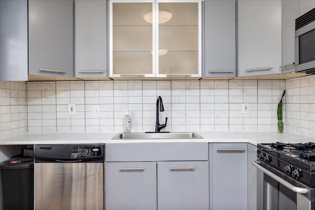 kitchen featuring gray cabinetry, decorative backsplash, sink, and appliances with stainless steel finishes