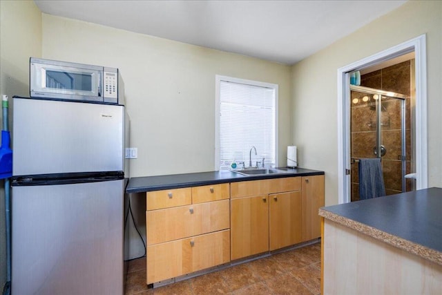 kitchen featuring sink, light brown cabinetry, and fridge