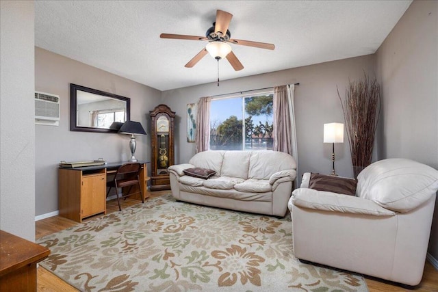 living room featuring a wall unit AC, ceiling fan, hardwood / wood-style floors, and a textured ceiling