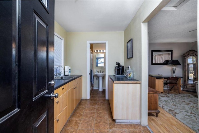 kitchen with a wealth of natural light, sink, a textured ceiling, and light brown cabinets