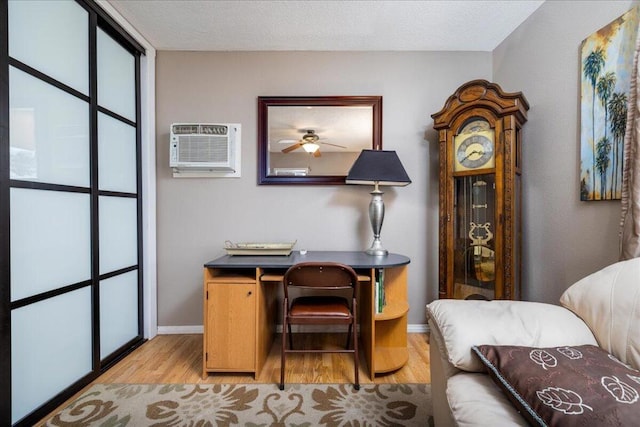 office space with an AC wall unit, ceiling fan, and light wood-type flooring