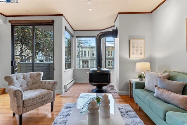 living room featuring baseboard heating, plenty of natural light, a wood stove, and ornamental molding