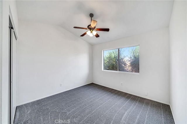 empty room with ceiling fan, lofted ceiling, and dark colored carpet