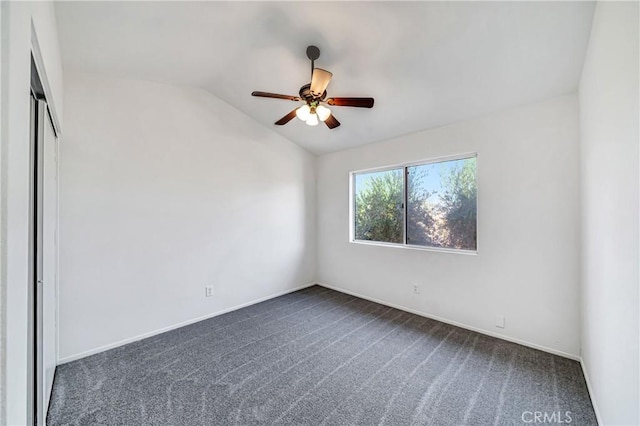 spare room with baseboards, vaulted ceiling, a ceiling fan, and dark colored carpet