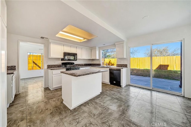 kitchen with black appliances, white cabinetry, visible vents, and a center island