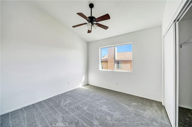 unfurnished bedroom with a closet, carpet flooring, vaulted ceiling, and baseboards