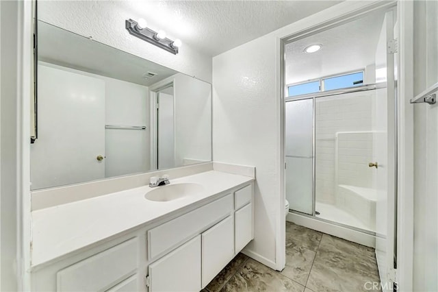 bathroom featuring a textured ceiling, a stall shower, vanity, and toilet