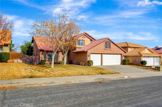 view of front facade with driveway, a garage, a tiled roof, fence, and stucco siding