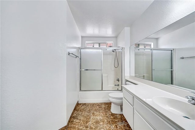 bathroom featuring vanity, toilet, and bath / shower combo with glass door