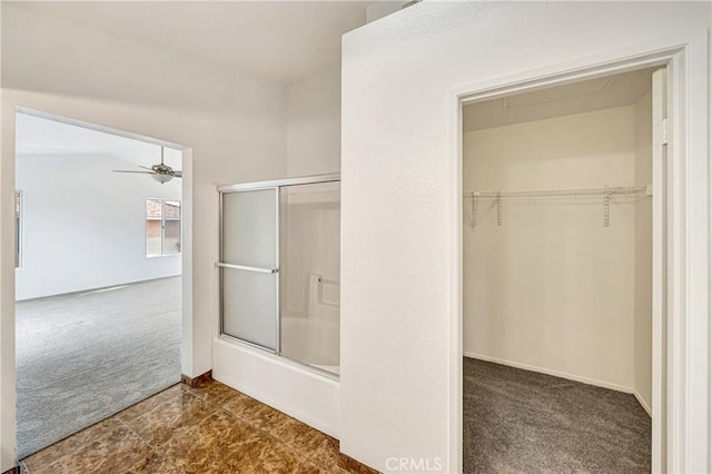 full bathroom featuring bath / shower combo with glass door, a spacious closet, and a ceiling fan