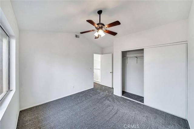 unfurnished bedroom with dark colored carpet, ceiling fan, a closet, and vaulted ceiling