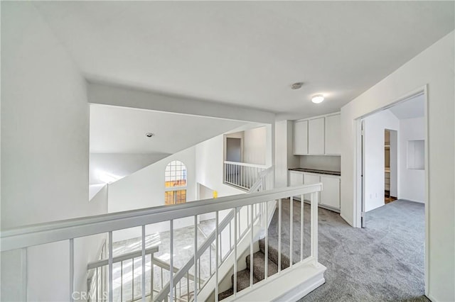 corridor with light carpet and an upstairs landing