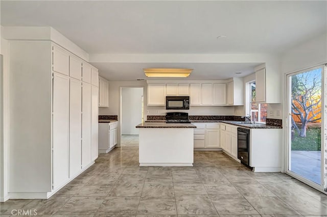 kitchen featuring a kitchen island, white cabinets, a sink, and black appliances