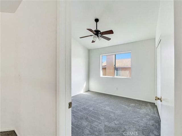 carpeted spare room featuring a ceiling fan and baseboards