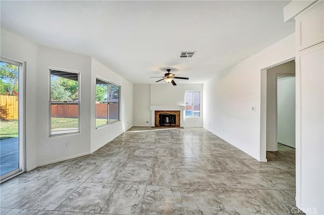 unfurnished living room with ceiling fan and a healthy amount of sunlight