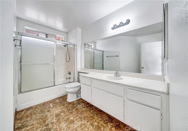 full bathroom with vanity, bath / shower combo with glass door, a textured ceiling, and toilet