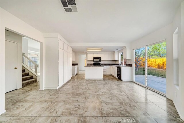 kitchen with sink, white cabinets, black appliances, and a kitchen island