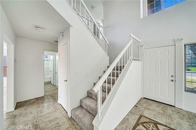 stairway featuring a towering ceiling