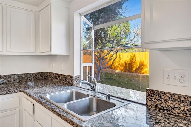 kitchen featuring white cabinets, sink, and dark stone counters