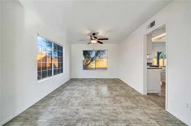 empty room featuring plenty of natural light, visible vents, and a ceiling fan