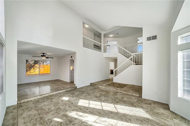 foyer entrance with a towering ceiling, ceiling fan, and a healthy amount of sunlight