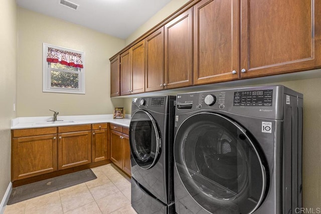 washroom featuring light tile patterned floors, sink, washing machine and clothes dryer, and cabinets