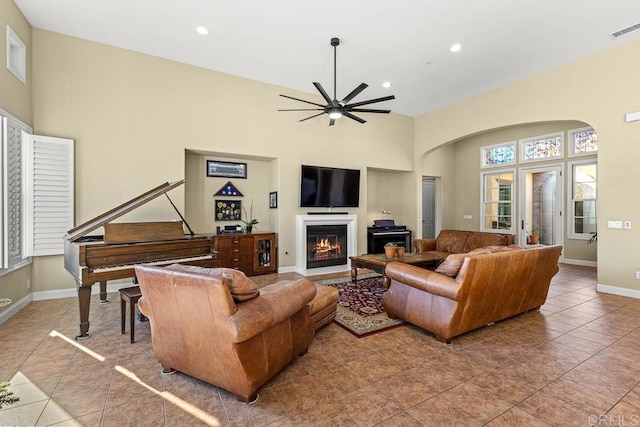 tiled living room with ceiling fan and a towering ceiling